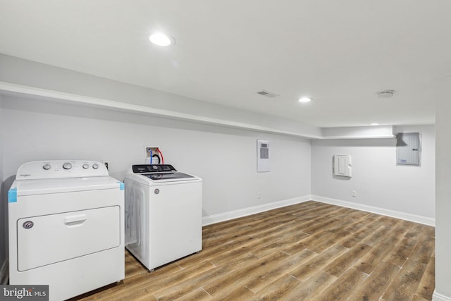 washroom with wood finished floors, baseboards, laundry area, electric panel, and washer and dryer