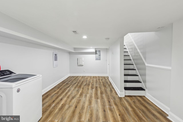 finished basement with electric panel, washer / clothes dryer, baseboards, and wood finished floors