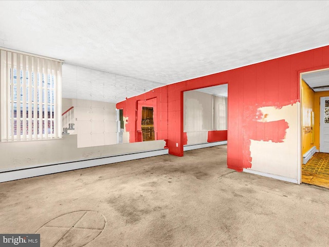 carpeted empty room featuring a textured ceiling and a baseboard heating unit