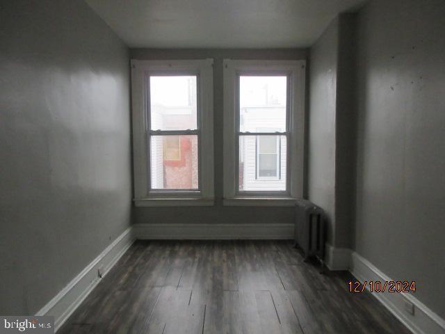 empty room with radiator heating unit and dark hardwood / wood-style floors