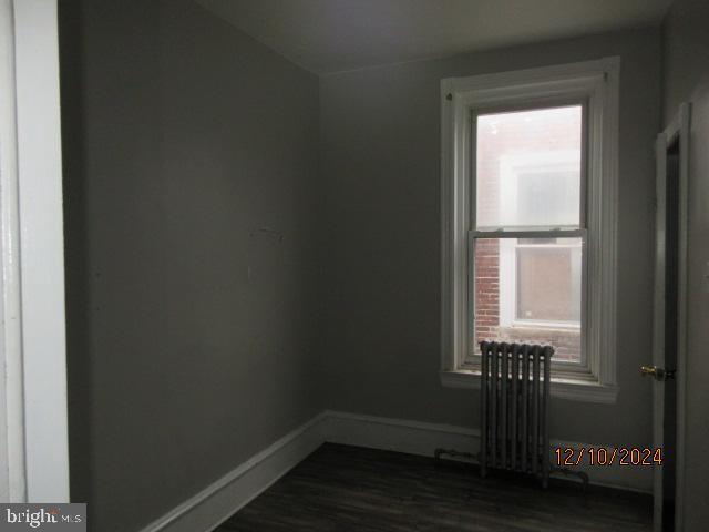 empty room featuring dark hardwood / wood-style flooring and radiator