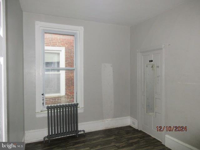 empty room with radiator and dark hardwood / wood-style floors