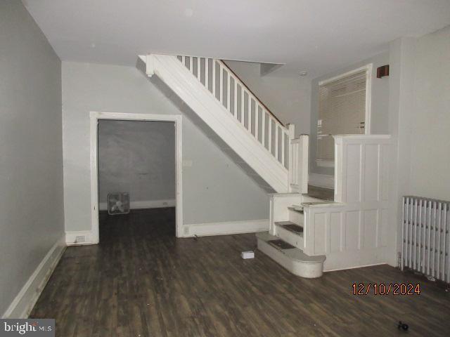 staircase with hardwood / wood-style floors and radiator heating unit