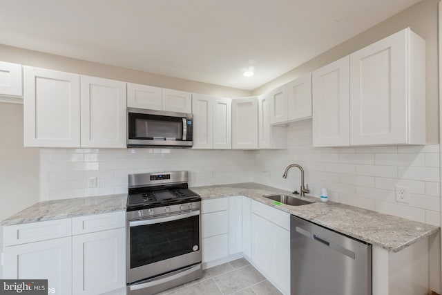 kitchen featuring decorative backsplash, white cabinetry, sink, and appliances with stainless steel finishes