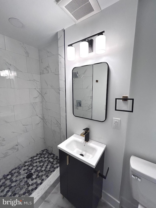 bathroom featuring tiled shower, vanity, and toilet