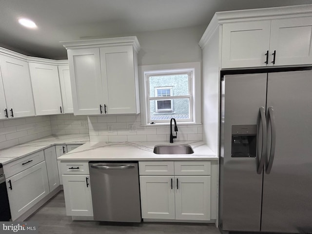 kitchen with backsplash, white cabinets, sink, light stone counters, and stainless steel appliances