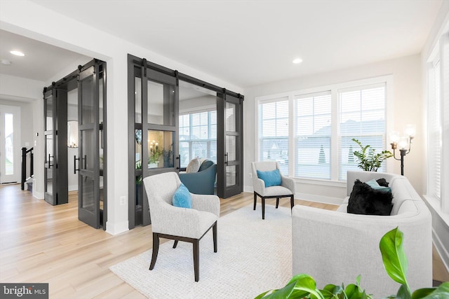 sitting room with a barn door and light hardwood / wood-style flooring