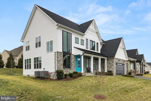 view of front of home featuring a front lawn, a garage, covered porch, and central AC