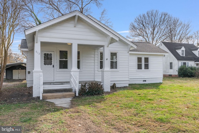 bungalow-style home with covered porch, a front yard, and a carport