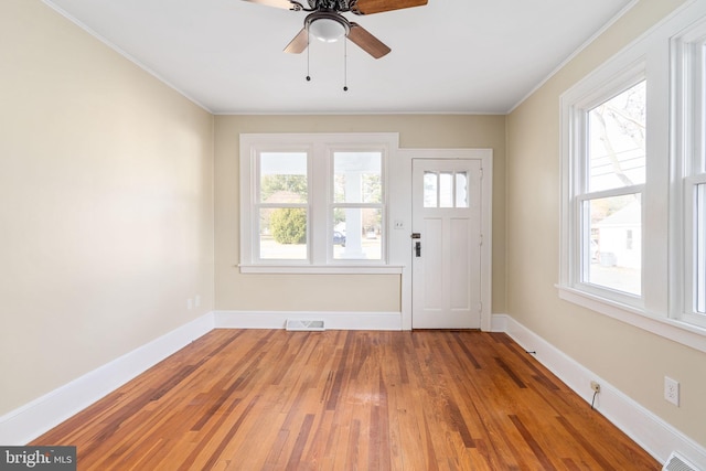 foyer entrance with a healthy amount of sunlight, wood-type flooring, and crown molding