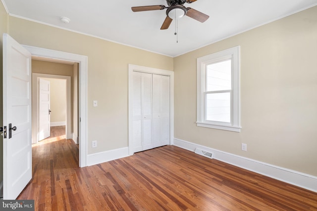 unfurnished bedroom featuring a closet, dark hardwood / wood-style floors, ceiling fan, and crown molding