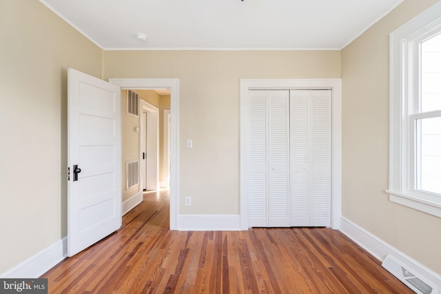 unfurnished bedroom with multiple windows, a closet, and dark wood-type flooring