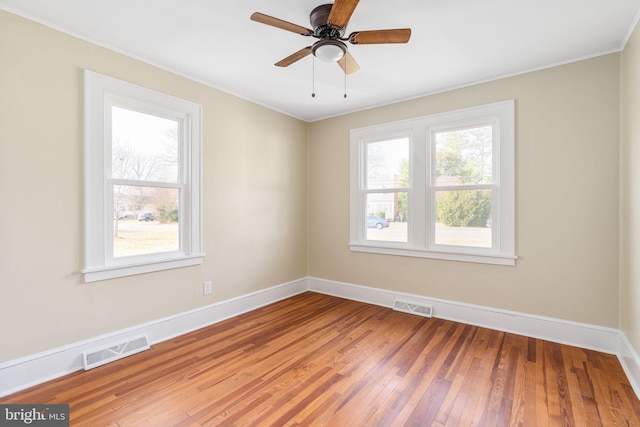 empty room with ceiling fan, plenty of natural light, crown molding, and hardwood / wood-style flooring