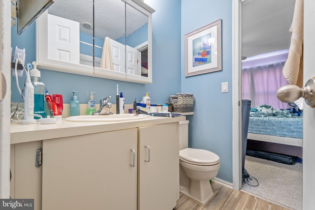 bathroom featuring hardwood / wood-style flooring, a textured ceiling, toilet, and vanity