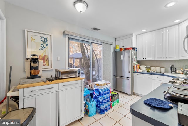 kitchen featuring dishwasher, high end refrigerator, white cabinetry, light tile patterned floors, and butcher block counters