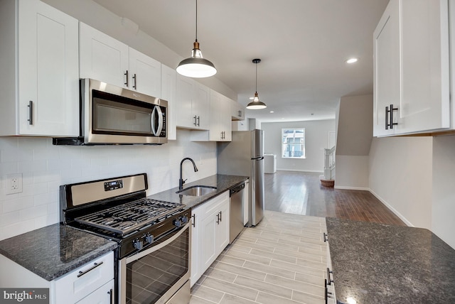 kitchen featuring white cabinetry, sink, stainless steel appliances, pendant lighting, and light wood-type flooring