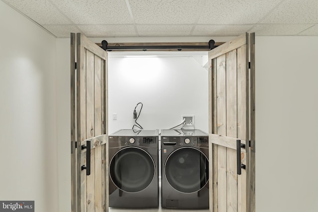 clothes washing area featuring washing machine and dryer and a barn door