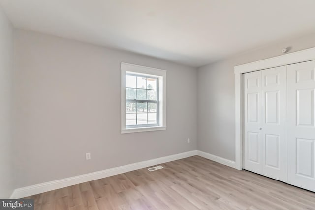 unfurnished bedroom featuring light wood-type flooring and a closet