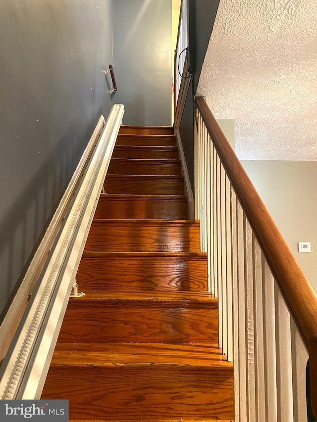 stairway featuring a textured ceiling