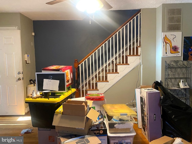 stairway with hardwood / wood-style flooring and ceiling fan