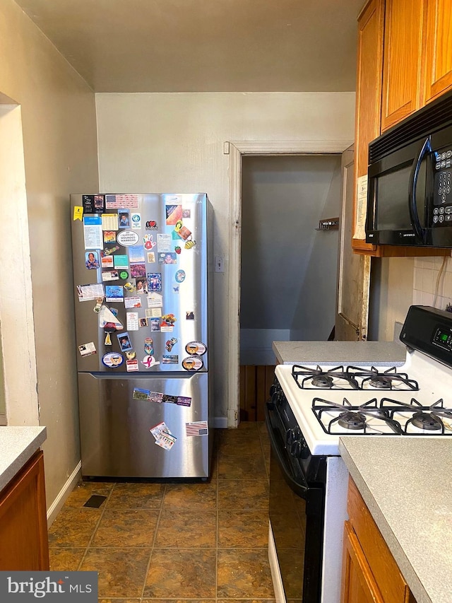 kitchen featuring backsplash, stainless steel fridge, and white gas stove