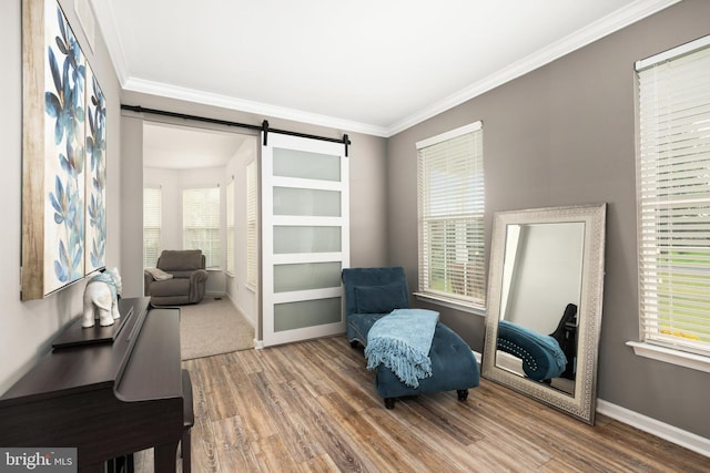 living area with hardwood / wood-style flooring, a barn door, and ornamental molding