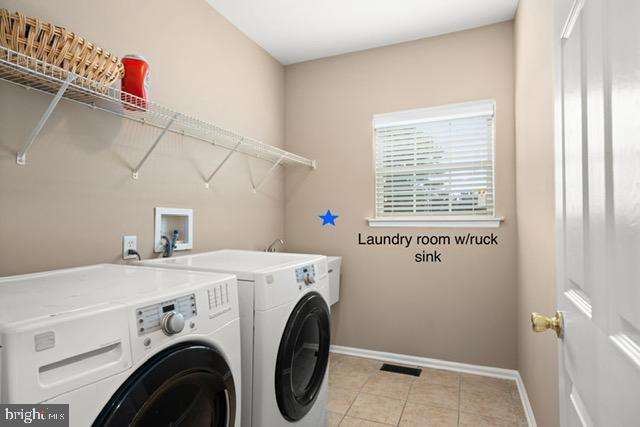 laundry room with independent washer and dryer and light tile patterned flooring