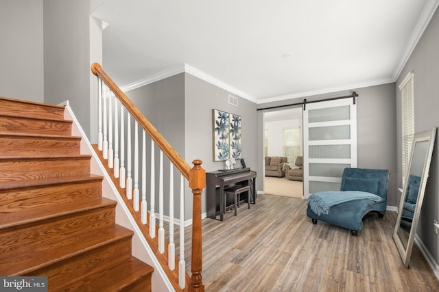 interior space featuring hardwood / wood-style floors, ornamental molding, and a barn door