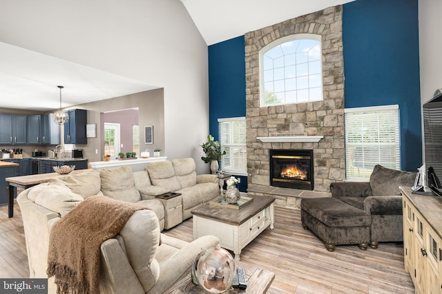 living room featuring light wood-type flooring, high vaulted ceiling, and a fireplace