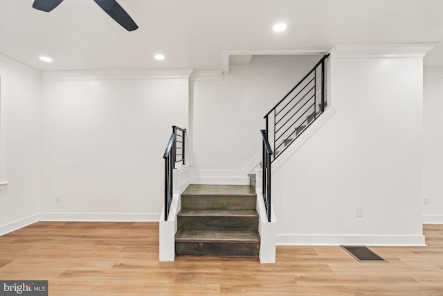 staircase with ceiling fan, crown molding, and hardwood / wood-style flooring