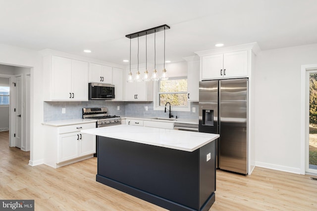 kitchen featuring appliances with stainless steel finishes, light hardwood / wood-style flooring, a kitchen island, and decorative light fixtures