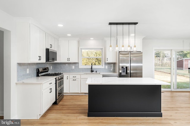 kitchen featuring a center island, sink, stainless steel appliances, light hardwood / wood-style floors, and pendant lighting