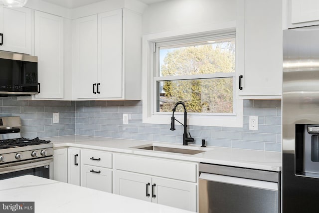 kitchen featuring decorative backsplash, appliances with stainless steel finishes, white cabinetry, and sink