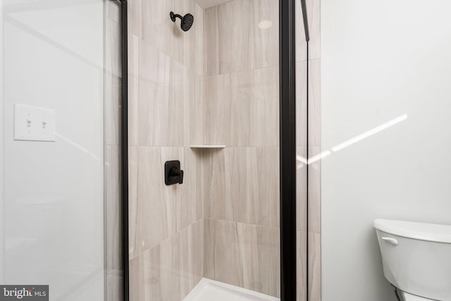 bathroom with tiled shower and toilet