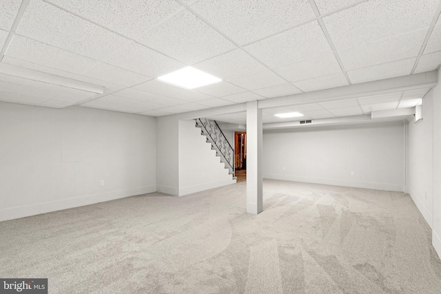 basement featuring a paneled ceiling and light carpet