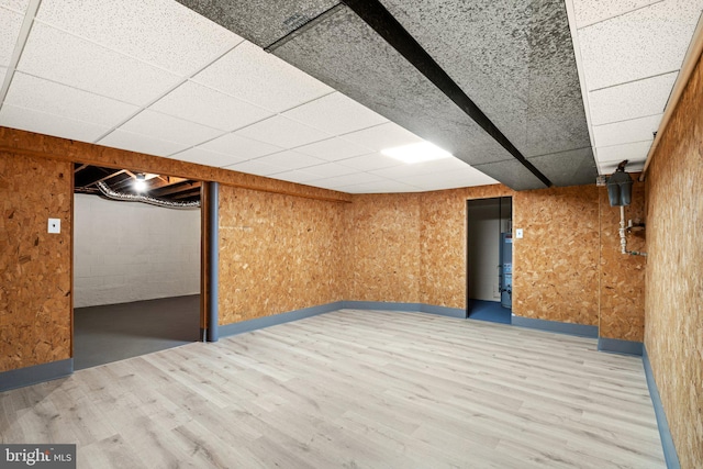 basement featuring a paneled ceiling and wood-type flooring