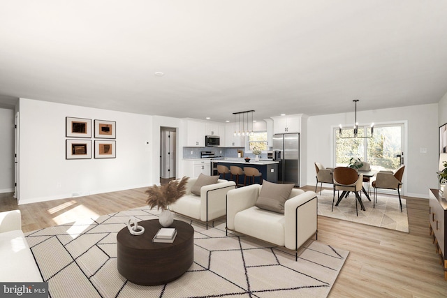 living room with an inviting chandelier and light wood-type flooring