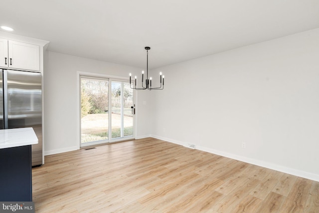 unfurnished dining area with light hardwood / wood-style floors and a notable chandelier