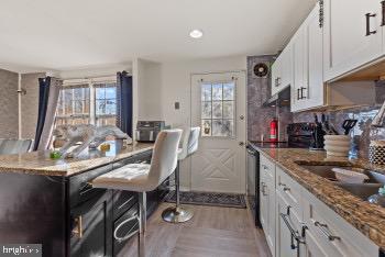 kitchen featuring a healthy amount of sunlight, white cabinetry, stone counters, and electric stove