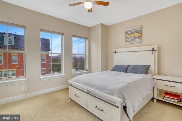 bedroom with ceiling fan, light colored carpet, and multiple windows