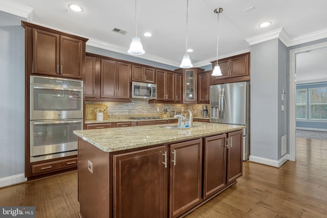 kitchen featuring sink, stainless steel appliances, hanging light fixtures, and a kitchen island with sink