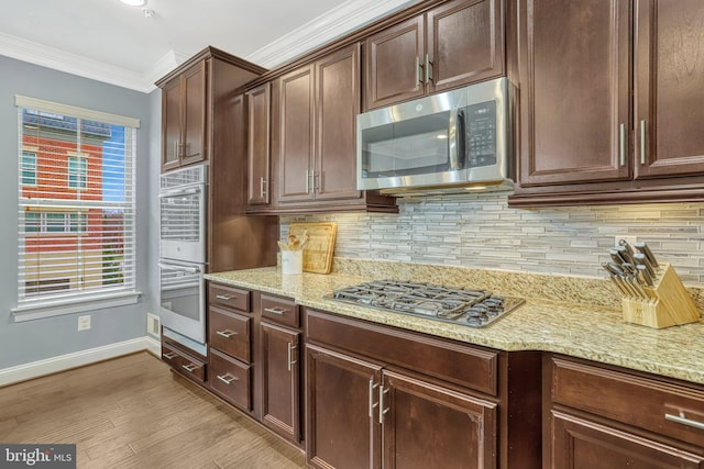 kitchen featuring light stone countertops, appliances with stainless steel finishes, tasteful backsplash, and ornamental molding