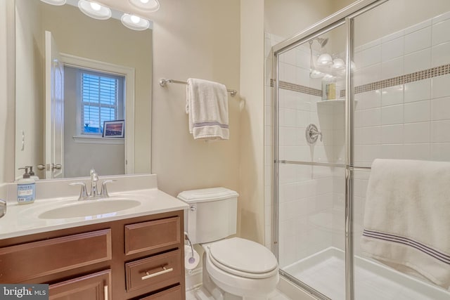 bathroom featuring vanity, toilet, and a shower with door