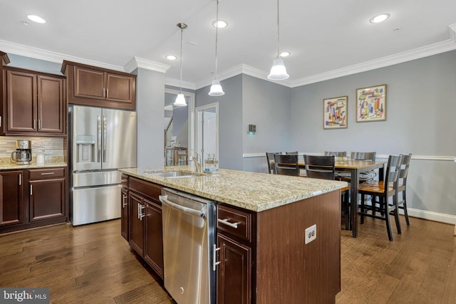 kitchen featuring sink, crown molding, decorative light fixtures, a center island with sink, and appliances with stainless steel finishes