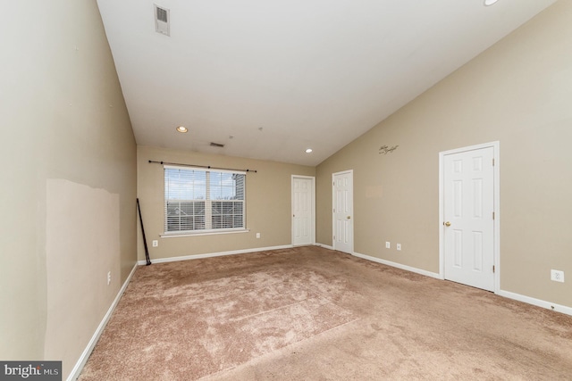 carpeted spare room featuring high vaulted ceiling