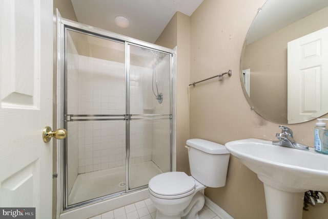 bathroom with tile patterned flooring, toilet, and a shower with shower door