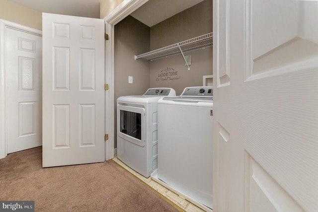 clothes washing area with separate washer and dryer and light carpet