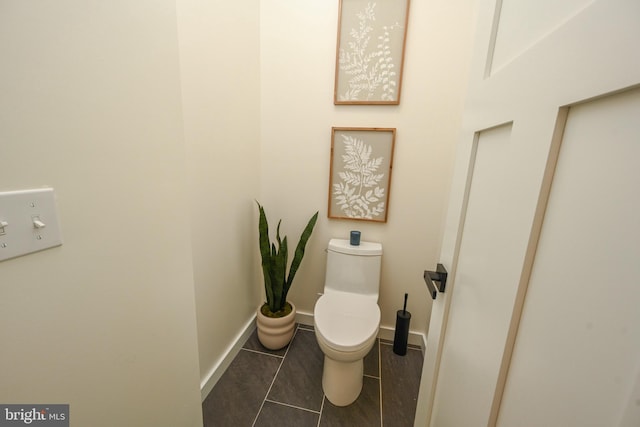 bathroom with toilet, baseboards, and tile patterned floors