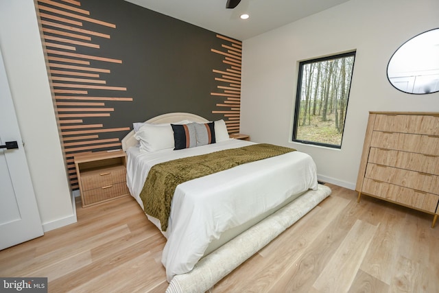 bedroom featuring wood finished floors, baseboards, an accent wall, and recessed lighting
