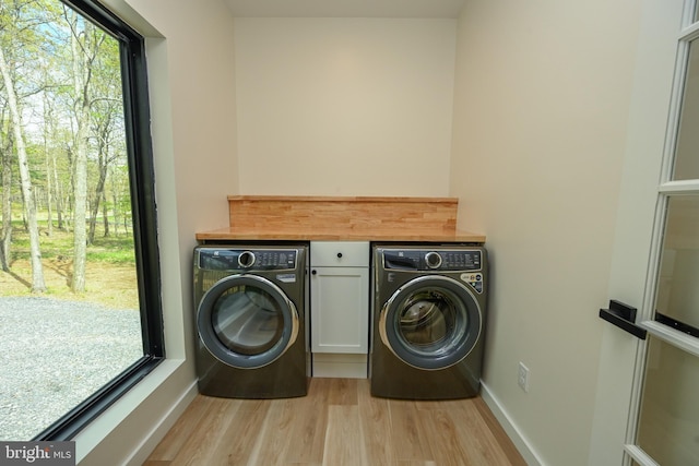 washroom with separate washer and dryer, light wood-style floors, and baseboards